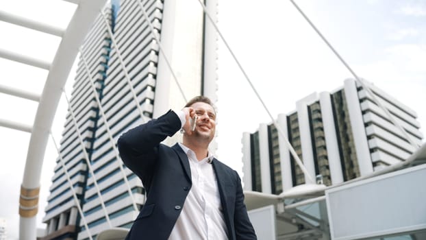 Smart caucasian businessman calling his colleague to plan financial strategy while standing at urban city. Project manager using his mobile phone to communicate with marketing team. Lifestyle. Urbane.