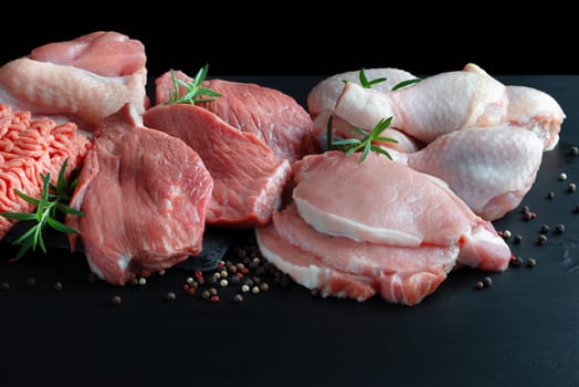 Different types of raw meat - beef, pork, lamb, chicken on a wooden board.