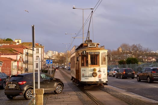 Porto, Portugal: Februray 22 2024 - Traditional vintage tram which is a symbol of Porto passes through the historical Linha 1 tram line