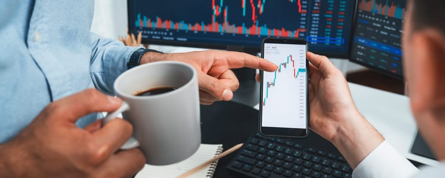Cropped image of stock traders with hands focusing on dynamic market data analysis, comparing with monitor screen on panorama view. Concept of discussing high profit value rate at workspace. Sellable.