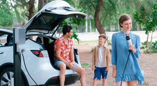 Family road trip vacation with electric vehicle, lovely family recharge EV car with green and clean energy. Natural and eco friendly car travel for sustainable environment. Perpetual