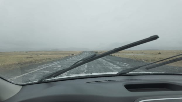Driving on a rainy day with continuous use of windshield wipers on a gravel road.