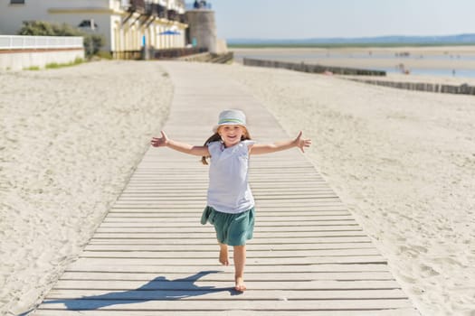 Little girl in a hat running on the beach