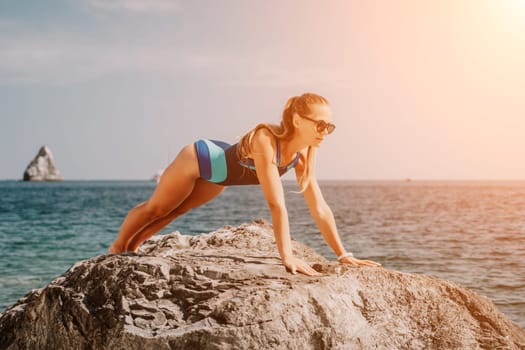 Woman sea yoga. Back view of free calm happy satisfied woman with long hair standing on top rock with yoga position against of sky by the sea. Healthy lifestyle outdoors in nature, fitness concept.