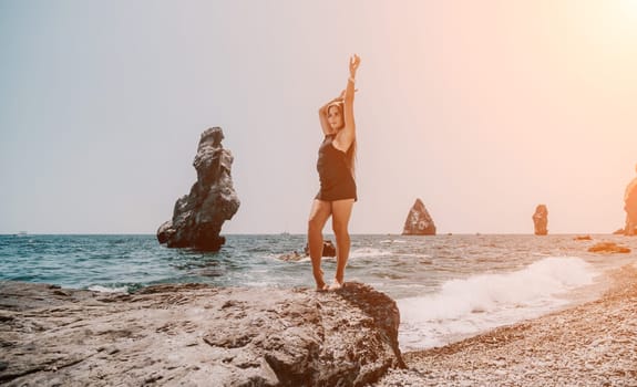 Woman travel sea. Young Happy woman in a long red dress posing on a beach near the sea on background of volcanic rocks, like in Iceland, sharing travel adventure journey