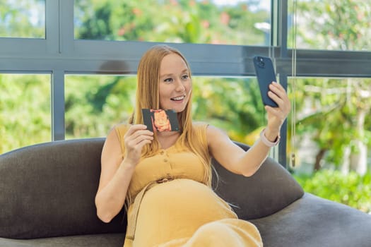 Excited woman shares the joy of motherhood, displaying an ultrasound photo of her child via a heartwarming video cal.