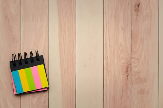 Colorful sticky notes on a textured, brown wooden table with a visible grain pattern for office supplies concept