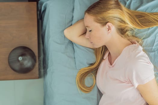 Expectant woman finds relaxation in bed, embracing tranquility with the help of an aroma diffuser during a moment of rest.