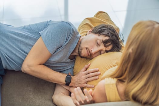 Tender moment as husband lovingly embraces his pregnant wife's belly while they lie together on the sofa, sharing warmth and anticipation.