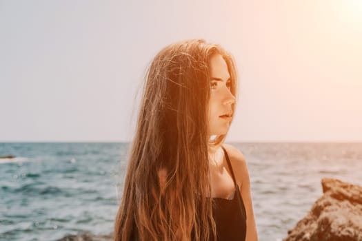 Woman travel sea. Young Happy woman in a long red dress posing on a beach near the sea on background of volcanic rocks, like in Iceland, sharing travel adventure journey