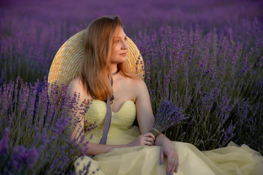 Woman poses in lavender field at sunset. Happy woman in yellow dress holds lavender bouquet. Aromatherapy concept, lavender oil, photo session in lavender.