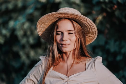 Woman with straw hat stands in front of vineyard. She is wearing a light dress and posing for a photo. Travel concept to different countries.