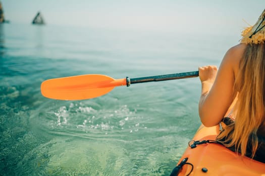 Woman in kayak back view. Happy woman with long hair in a swimsuit and hat floating in kayak on the sea. Summer holiday vacation. Summer holidays vacation at sea