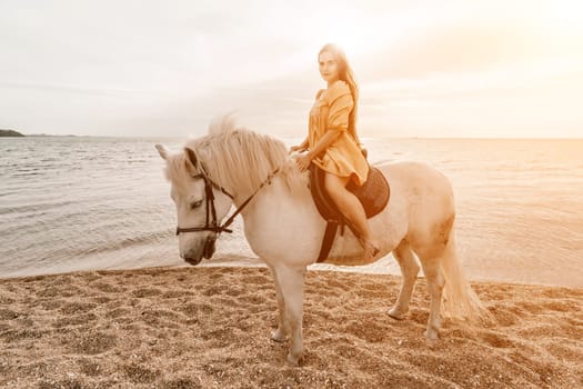 A woman in a dress stands next to a white horse on a beach, with the blue sky and sea in the background