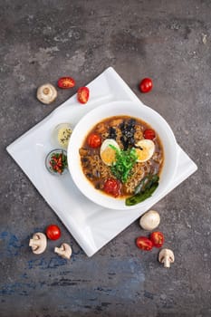 A steaming bowl of traditional Japanese ramen, filled with savory broth, springy noodles, and topped with an assortment of fresh vegetables and tender slices of pork.