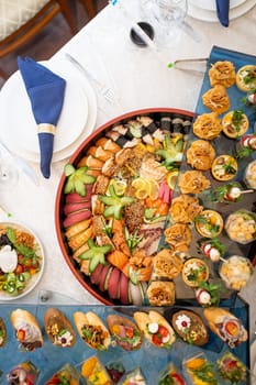 An opulent buffet showcasing a lavish assortment of fresh seafood, sushi, salads, fruits, and pastries, beautifully arranged on a pristine white tablecloth for a luxurious and celebratory event.