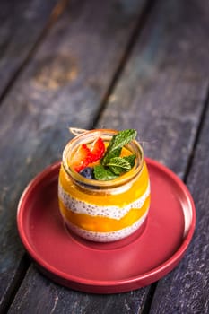 Chia seed pudding with mango, mixed berries, milk, Greek yogurt, assorted fruit, and honey. Tropical-inspired delight for a refreshing summer treat.