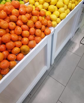 A counter with fresh tropical fruits, tangerines and lemons, close-up, vertical.
