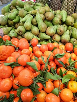 Vertical organic background of tropical fruits, ripe tangerines and green pears.