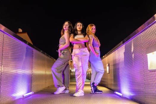 Low angle view portrait of a group of young female freestyle and hip hop dancers outdoors at night