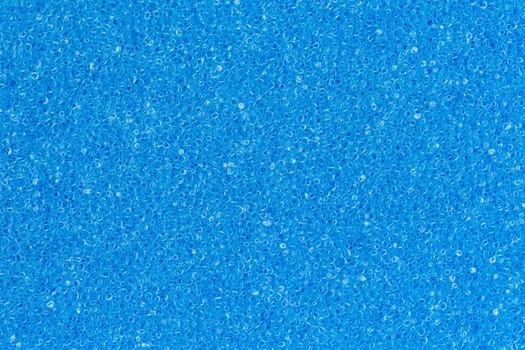 Foam sponge porous texture background deep sky blue color. Extreme close-up view of unique detail abstract synthetic material. Horizontal composition for design, colored decoration backdrop