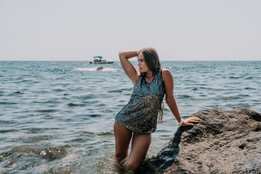 Woman travel sea. Young Happy woman in a long red dress posing on a beach near the sea on background of volcanic rocks, like in Iceland, sharing travel adventure journey