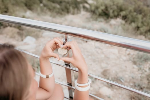 Hand, lock, heart, love, valentines day. Close up view of a woman holding a heart shaped lock that is locked onto a chain link fence.