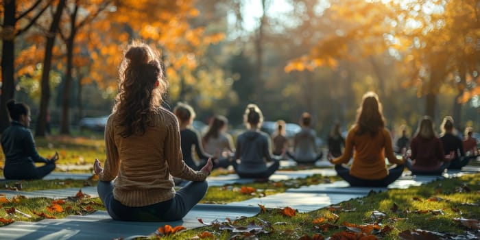 Group of adults attending a yoga class outside in park with natural background.