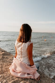 Woman travel sea. Young Happy woman in a long red dress posing on a beach near the sea on background of volcanic rocks, like in Iceland, sharing travel adventure journey