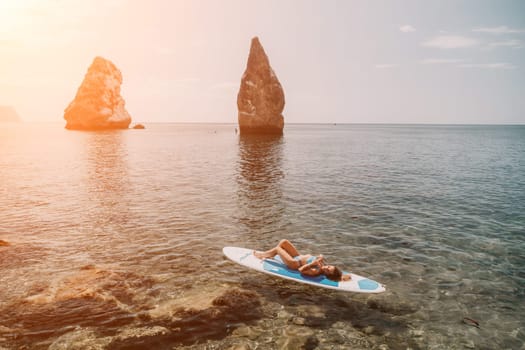 Woman sup yoga. Middle age sporty woman practising yoga pilates on paddle sup surfboard. Female stretching doing workout on sea water. Modern individual hipster outdoor summer sport activity