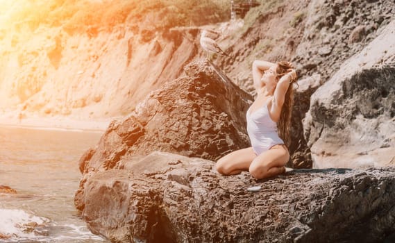 Woman travel sea. Young Happy woman in a long red dress posing on a beach near the sea on background of volcanic rocks, like in Iceland, sharing travel adventure journey