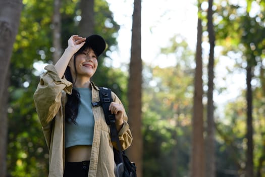 Attractive young woman with backpack trekking in forest, exploring nature. Traveling concept.
