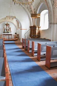 Christian, shrine or altar in church for religion, worship and spiritual space for ceremony in Danish culture. Praise, god and sculpture of Jesus in chapel with furniture, seat on aisle and hallway.
