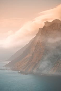 Mountain, fog and ocean landscape with cliff, cloudy sky and tropical island sunset for travel location. Nature, sea and sustainable environment with earth, natural hill and holiday destination