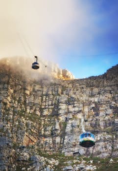 Nature, clouds and blue sky with aerial cable car on Table Mountain for outdoor adventure, travel destination and sightseeing. Low angle, national landmark and tourism for peace, calm and relax