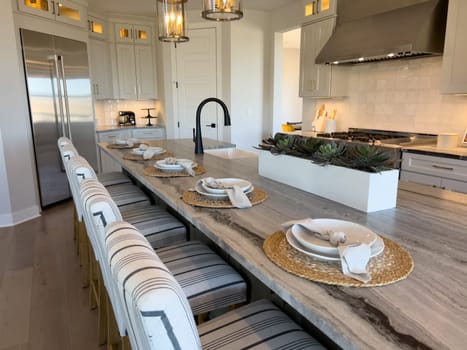Denver, Colorado, USA-February 29, 2024-This inviting kitchen boasts a long dining table set for a family meal, with modern pendant lighting overhead and a sleek kitchen island that promises memorable gatherings and culinary adventures.