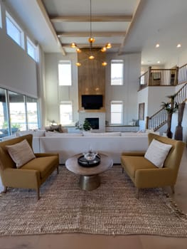 This expansive living room is defined by high ceilings and large windows, complemented by warm mustard armchairs and a central statement coffee table, crafting a welcoming yet upscale ambiance.