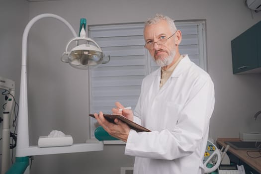 Portrait of attractive handsome dentist with haircut, white lab coat.