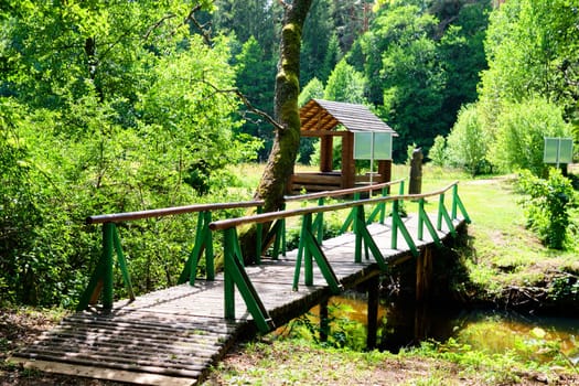 A wooden bridge over the stream leading to the gazebo