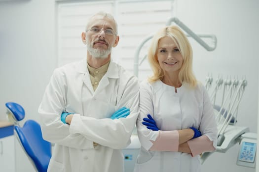 Male and female dental doctors wearing face sitting at his clinic. High quality photo