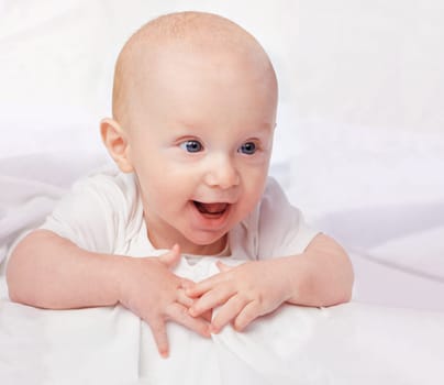 Baby, excited and smile with laying on bed for curiosity, child development and relax on bed at house. Adorable, kid and cute infant in home for playful, laugh and fun with happiness in nursery.