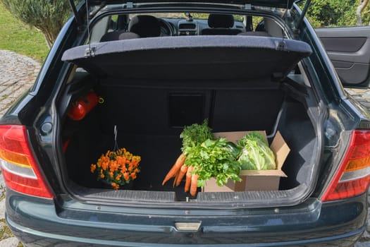 cardboard box with an assortment of fresh vegetables stands in the trunk of a car, natural products and healthy eating, the concept of cooking at home, high quality photo