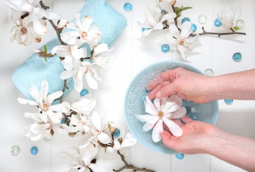 Hands of a young girl with natural manicure and a bowl of water with white magnolia flowers, spa treatments and massage, cosmetology personal care, High quality photo