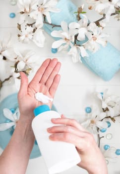 young woman doing step by step hand massage with cream in salon with cup of spring water and blue spa stones and white magnolia flowers, High quality photo