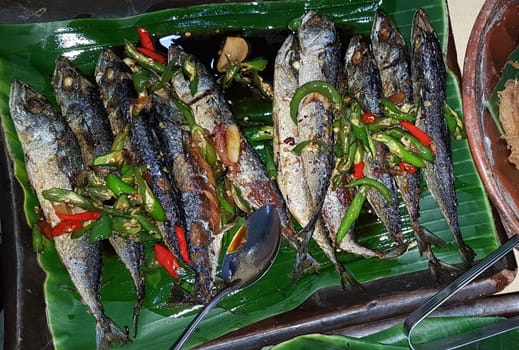 Seafood dish served on the table and plate from above with different kind of dish from fried fish barracuda, snapper, tuna jaws, and also mix of tropical vegetables and sambal or chili paste