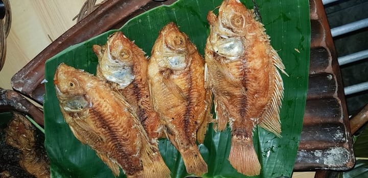 Seafood dish served on the table and plate from above with different kind of dish from fried fish barracuda, snapper, tuna jaws, and also mix of tropical vegetables and sambal or chili paste