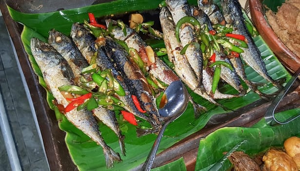 Seafood dish served on the table and plate from above with different kind of dish from fried fish barracuda, snapper, sardines, and also mix of tropical vegetables and sambal or chili paste