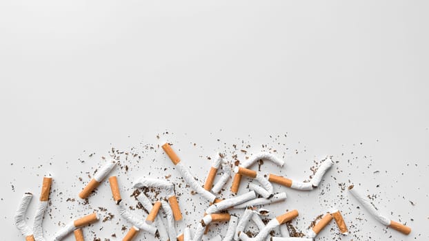 Discarded crushed broken cigarettes and scattered tobacco on white background, representing cessation and the end of smoking with copy space. No tobacco day. High quality photo