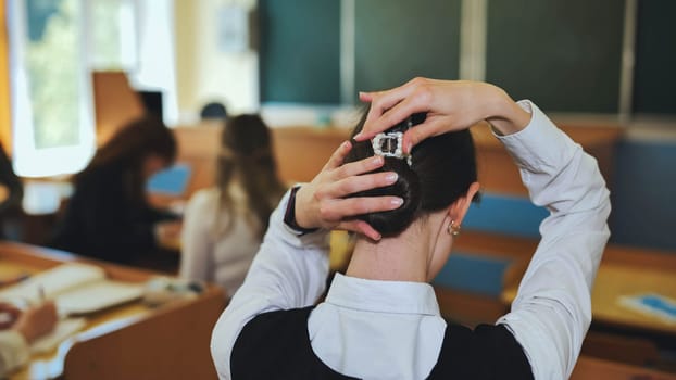 A schoolgirl fixes her hair during class