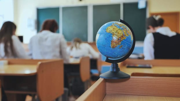 A globe of the world in a school classroom during a lesson. The globe shows Africa and Eurasia.